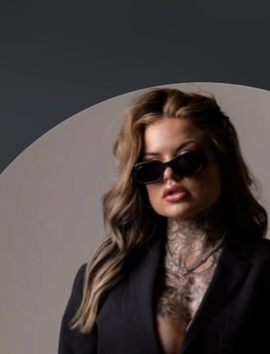 Cheyenne Somer in black blazer and sunglasses against a softly lit studio backdrop